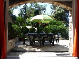 una mesa y sillas con una sombrilla verde en Appartement Castagniers, en Castagniers