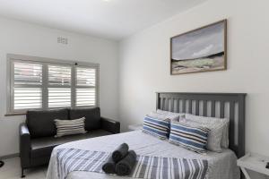 a bedroom with a bed and a chair in it at Salt & Soul Stay in Gordonʼs Bay
