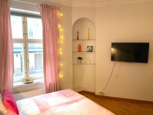 a bedroom with a bed and a tv and a window at Pink Gem, Kamppi in Helsinki