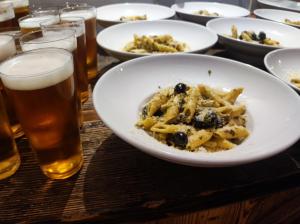 a table with plates of food and glasses of beer at Greg&Tom Beer House Hostel in Krakow