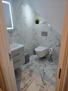 a marble bathroom with a toilet and a sink at West Hendon Apt with Parking in The Hyde