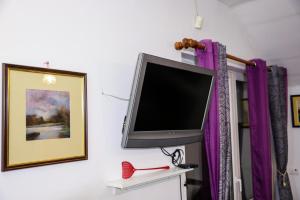 a flat screen tv on a wall with purple curtains at Zvezdana noc in Zvezdara