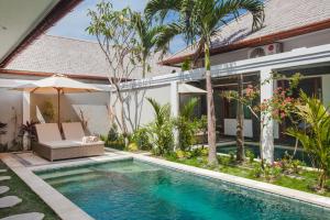 a villa with a swimming pool in front of a house at Two Lizards Beach Villas in Sanur