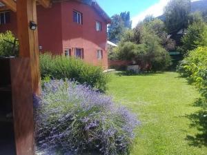 un patio con una casa y algunas flores púrpuras en Cabañas Alegría del Lago, en Lago Puelo 11 fotos más