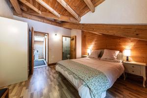 a bedroom with a large bed with a wooden wall at Chalet Abricotine, sleeps 10, Hot tub in Saint-Jean-dʼAulps +6 photos