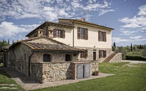 a large stone building with a grassy yard at Podere Il Gioiello in San Gimignano