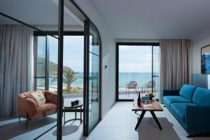 - un salon avec un canapé bleu et une vue sur l'océan dans l'établissement Harmony Boutique Resort - Adults oriented, à Georgioúpoli
