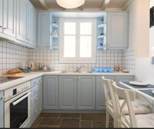 a white kitchen with blue cabinets and a window at Maridina House in Livadi