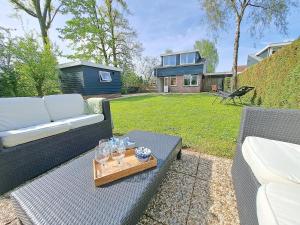 a patio with a couch and a tray of wine glasses at Charmante vakantiewoning met Sauna, Zeeland, VP002 in Heinkensand
