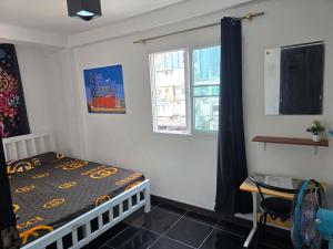 a bedroom with a bed and a desk and a window at Jatujak Bangkok guesthouse R 03-06 in Sathani Bang Su