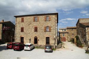 ein großes Steingebäude mit Autos auf einem Parkplatz in der Unterkunft Borgo al Cielo - Albergo Diffuso in Suvereto