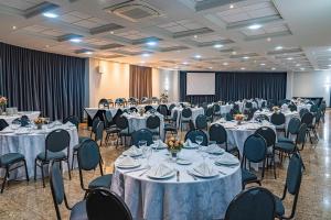 a banquet hall with tables and chairs and a screen at Hotel Metrópole Maringá in Maringá +112 photos