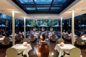 een restaurant met witte tafels en stoelen en grote ramen bij The Mandala Berlin, a Member of Design Hotels in Berlijn