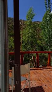 a chair on a deck with a view of a hill at Potrerillos Rio Blanco Tiny, cabaña a orillas del Rio Blanco en Potrerillos in Potrerillos +15 photos