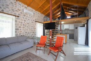 a living room with a couch and orange chairs at Sora No Mori Village in Marmaris