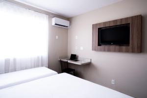 a hotel room with two beds and a flat screen tv at Hotel Conceição in Linhares