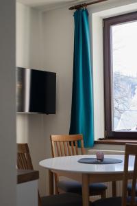 a dining room table with chairs and a blue curtain at Penzion U Lípy in Velké Karlovice