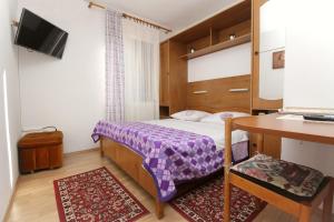 a small bedroom with a bed and a table and a desk at Rooms Grozdana in Baška
