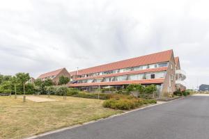 a large building with a red roof on the side of a road at Vakantiewoning Bruinisse aan Jachthaven Zeeland, VP012 in Bruinisse