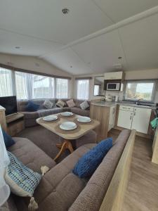 ein Wohnzimmer mit Sofa und Tisch in der Unterkunft Cosy Perranporth caravan, Cornwall in Perranzabuloe