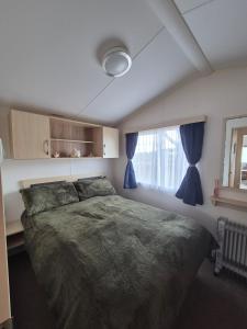 ein Schlafzimmer mit einem großen Bett und einem Fenster in der Unterkunft Cosy Perranporth caravan, Cornwall in Perranzabuloe + 20 Fotos