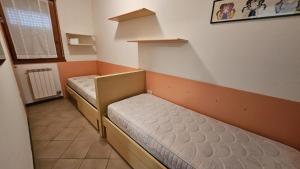 a small room with two beds and a window at Villaggio Tirreno appartamento 02 in Rosolina Mare