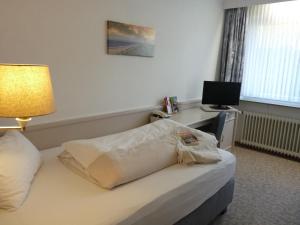 a hotel room with a bed and a desk with a television at Hotel zum Rosenteich in Bad Zwischenahn