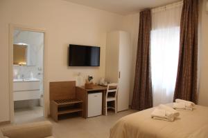 サレルノにあるNina Suitesのベッドと机とテレビがあるホテルの部屋