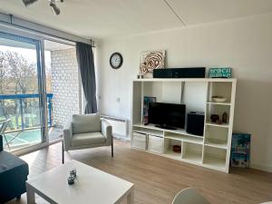 a living room with a tv and a couch and a table at Appartement Badhotel 324 in Callantsoog