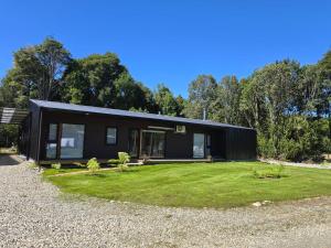 a black house with a large yard at Apartamento campestre 2 dormitorios con terraza in Puerto Varas