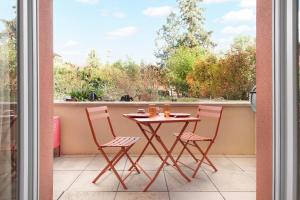 a table and chairs on a balcony with a window at Oasis Cachée - Jacuzzi et cinéma in Toulouse