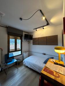 a bedroom with a bed and a desk and a table at The Orange Teddy Bear Hostal La Peña in Mieres
