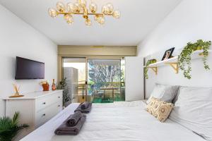 Un dormitorio con una gran cama blanca con una lámpara de araña. en Beaurivage, en Menton