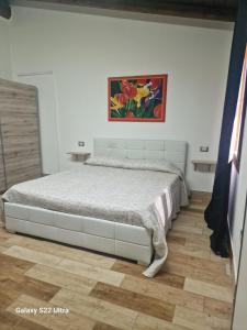 a bed in a bedroom with a painting on the wall at Case Vacanza Marganai - Via Zagabria 36 in Iglesias +37 photos