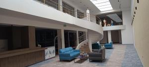 a lobby with a spiral staircase and blue chairs at Viazo Apartment in Dolný Kubín