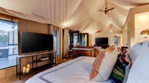 a bedroom with a bed with a flat screen tv at The Covery the Wren House a luxury African tent retreat on stocked bass pond in Hot Springs