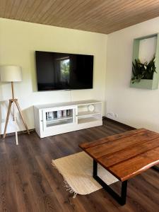 a living room with a tv and a wooden table at Ferienwohnung Wiesental in Kohlstetten