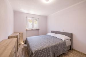 a white bedroom with a bed and a window at Vila Nina - Apartment Valentina in Vinišće
