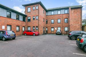 a large brick building with cars parked in a parking lot at Stylish flat in the heart of Hitchin with free parking in Hitchin