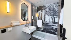 a bathroom with a sink and a shower with a mirror at Campanile NATURE - Bollene in Bollène +32 photos