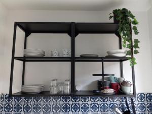 a black shelf with plates and dishes on it at Wohnung im Grünen in Messenähe in Meerbusch