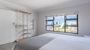 a bedroom with a white bed and a large window at The Famous Bokaap Villa in Cape Town