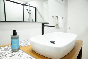 a bathroom with a white sink and a bottle of soap at Welcome A Casa de Pedra in O Grove