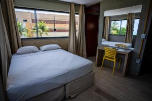 a bedroom with a bed and a desk and a window at Bessa Golden Flats in João Pessoa