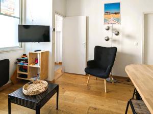 ein Wohnzimmer mit einem schwarzen Stuhl und einem TV in der Unterkunft **Arcachon Centre: T3 Moderne avec Terrasse, Proche Plage et Commerces pour 4 Personnes** - FR-1-420-112 in Arcachon
