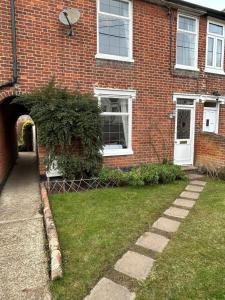 ein Backsteinhaus mit einem Torbogen im Hof in der Unterkunft Victorian Woodbridge cottage in Melton
