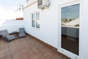 einen Balkon mit 2 Stühlen und einem Fenster in der Unterkunft Hotel Familia Conde in Huelva