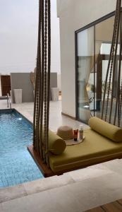 a swimming pool with a yellow bench next to a house at Private Pool Villa Rawaq Chalet in Āsam