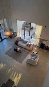 a living room with couches and tables and windows at Private Pool Villa Rawaq Chalet in Āsam