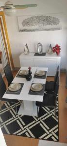 einen weißen Tisch mit schwarzen Stühlen und einen weißen Tisch mit Tellern in der Unterkunft Vistabella golf villa jade in Orihuela